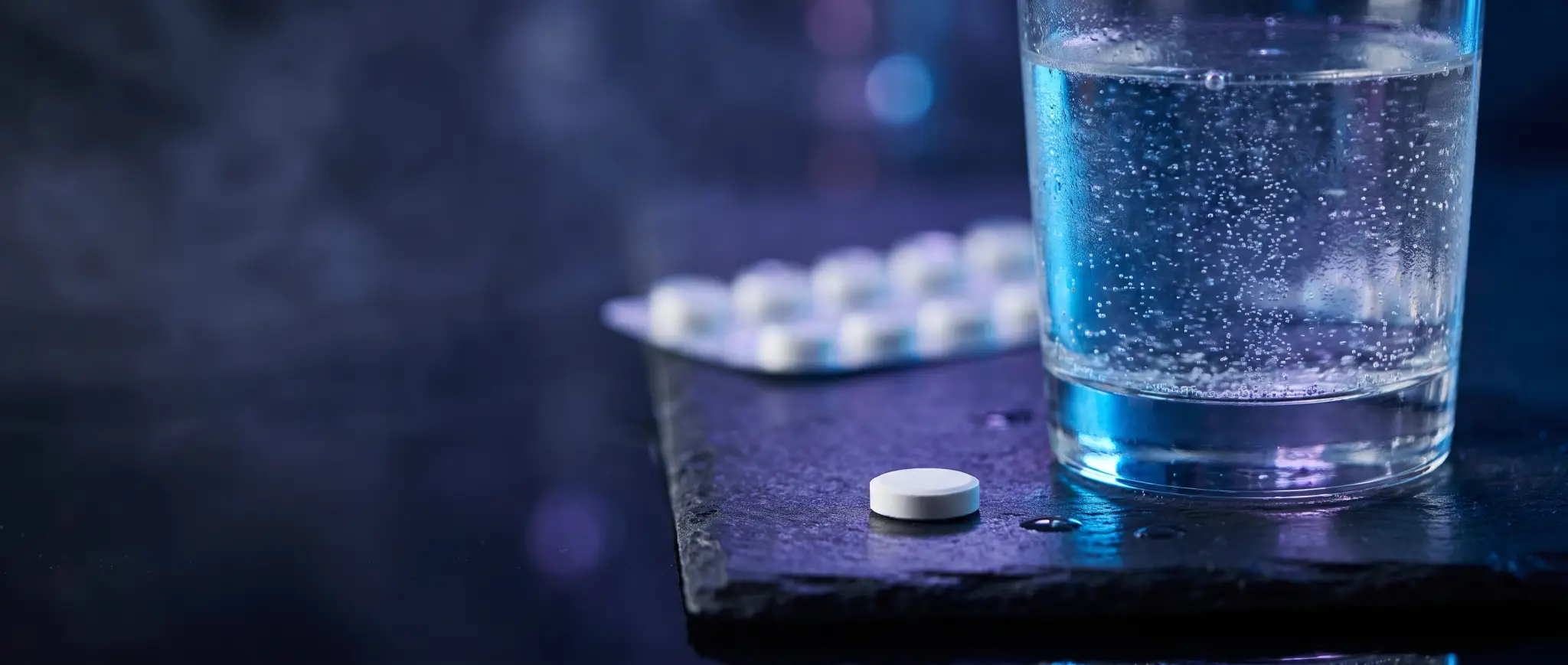 A single oral semaglutide tablet rests beside a small glass of water on a clinical surface.