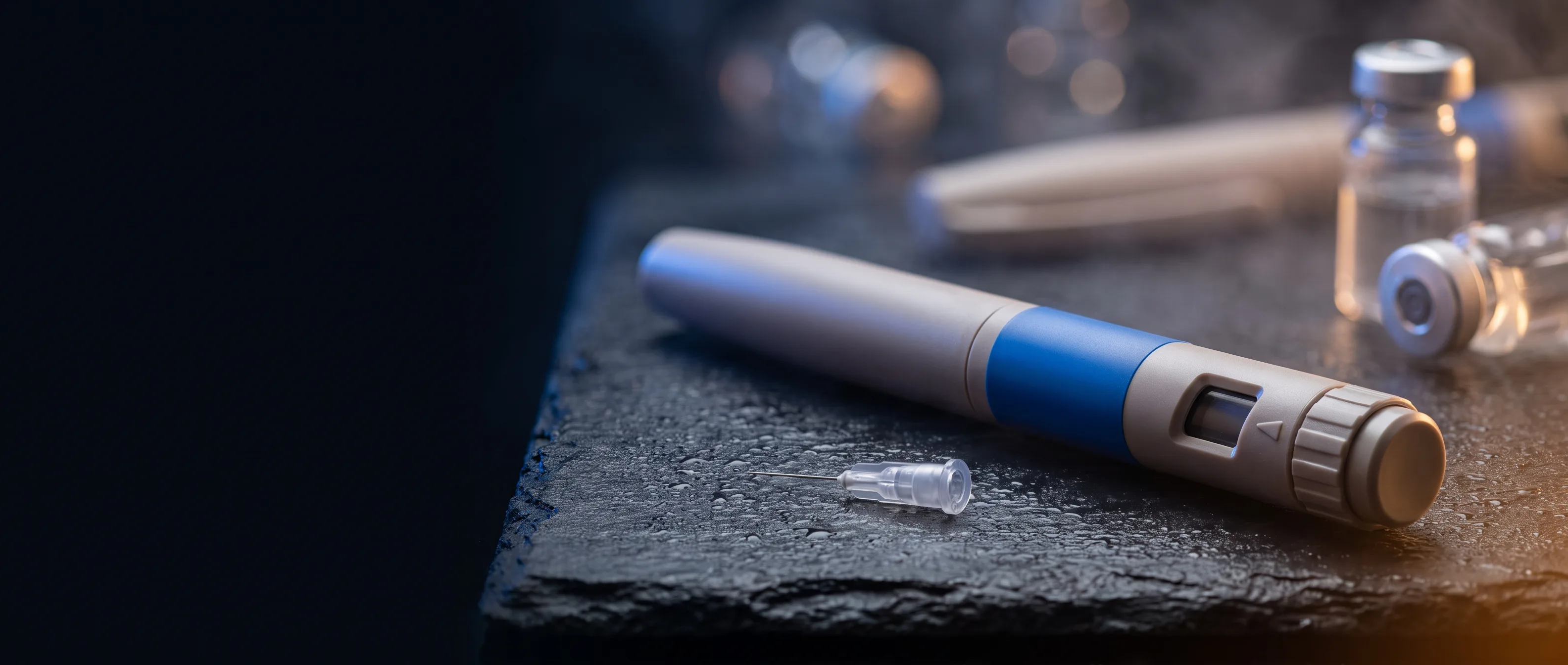 Semaglutide injection pen with dose dial and fine pen needle resting on a dark slate surface.